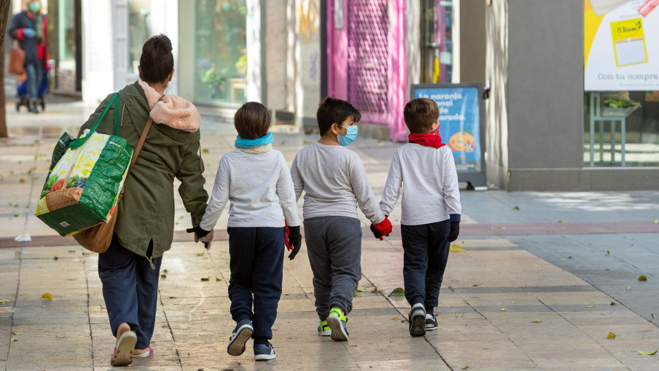 Una madre y sus hijos con mascarilla tras hacer la compra en Zaragoza. EFE