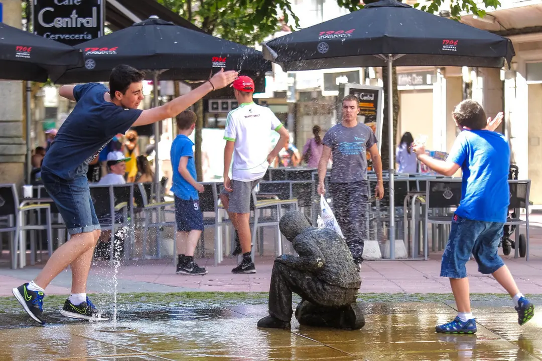 J&oacute;venes juegan y se refrescan en una de las fuentes de la ciudad
