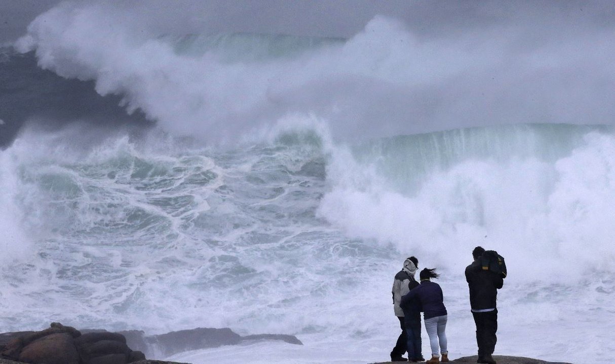 Varios turistas observan las olas en Muxía