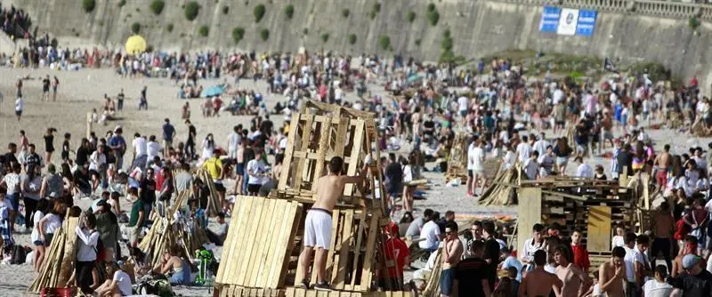 Multitud de personas preparan las tradicionales hogueras en la playa del Orzán