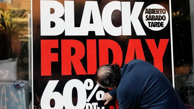 Un hombre coloca un cartel del Black Friday. JUAN CARLOS CÁRDENAS (EFE)