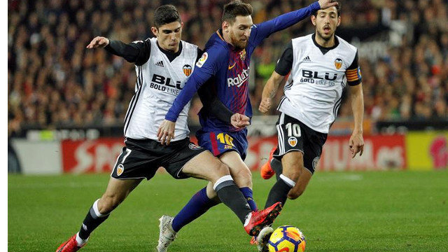 Messi intenta llevarse el balón ante dos jugadores del Valencia. MANUEL BRUQUE (EFE)