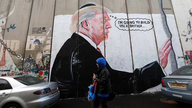 Una mujer camina junto a un graffiti del presidente de EE.UU., Donald Trump, en el muro de separación israelí de la ciudad cisjordana de Belén. ABED AL HASHLAMOUN