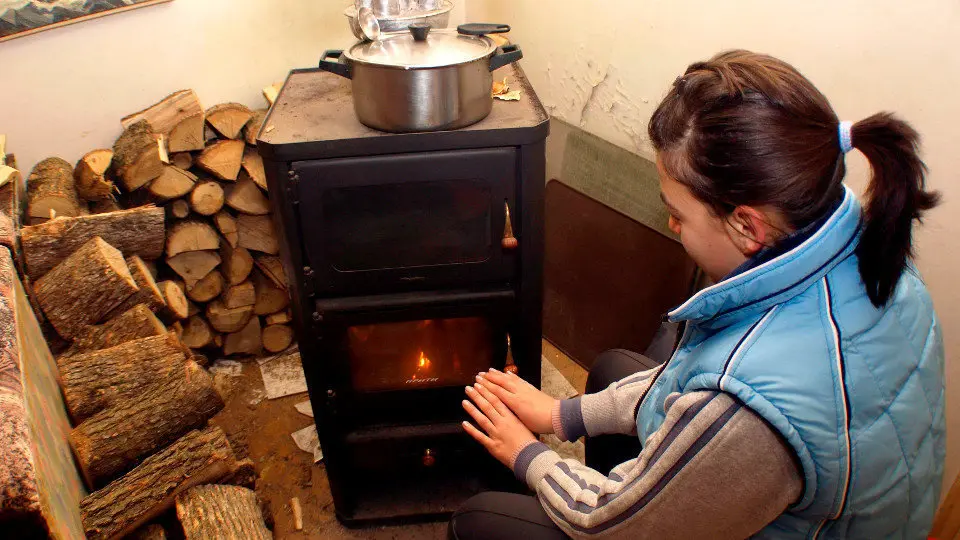 Una mujer se calienta junto a una estufa. AEP