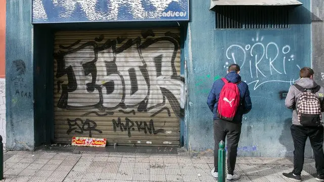 Unos jóvenes miran la puerta del bar a cuyas puertas fue agredido Víctor Laínez. JAVIER CEBOLLADA (EFE)