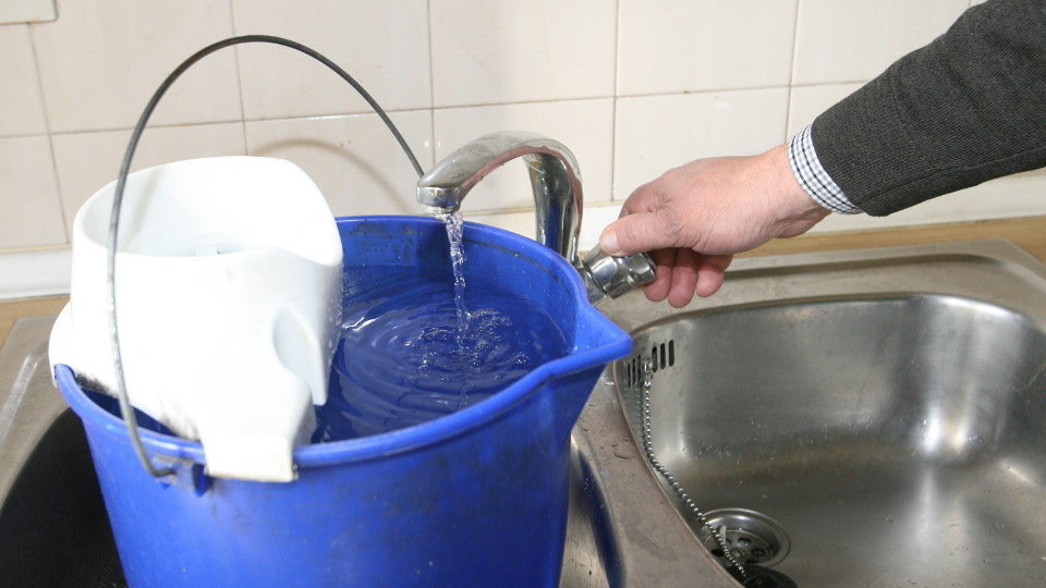 Un hombre llena un cubo de agua en su domicilio. TOÑO PARGA - Sequía