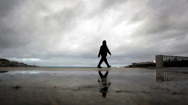 Un hombre camina por el paseo marítimo de A Coruña bajo el cielo nublado. CABALAR (EFE)