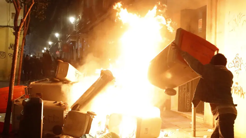 Un hombe arroja un contenedor a las llamas en los dsiturbios de Lavapiés.JAVIER LIZÓN (Efe)