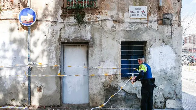 Un agente de la Guardia Urbana inspecciona el edificio tras el incendio. ENRIC FONTCUBERTA (EFE)