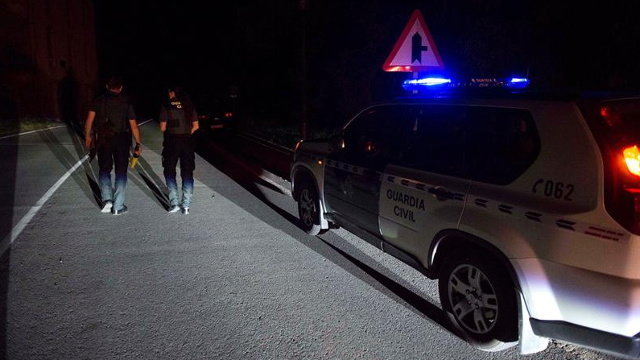 Dos agentes de la Guardia Civil cortan la carretera que da acceso a la casa de Turieno. EFE