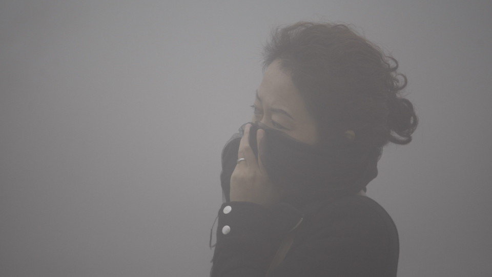 Una mujer se cubre la cara para atravesar una nube de contaminación en China. EFE