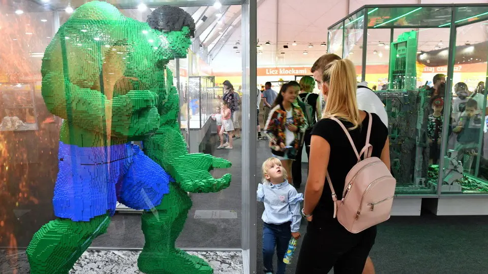 Unha familia diante dun superheroe feito con pezas de Lego. EFE