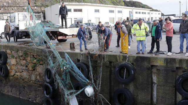 Traballadores do porto de Malpica recollen a rede do pesqueiro O Silvosa, que se afundiu de madrugada no propio porto. LAVANDEIRA JR (EFE)