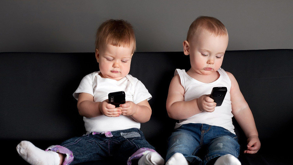 Niños pequeños con móviles en la mano. EP