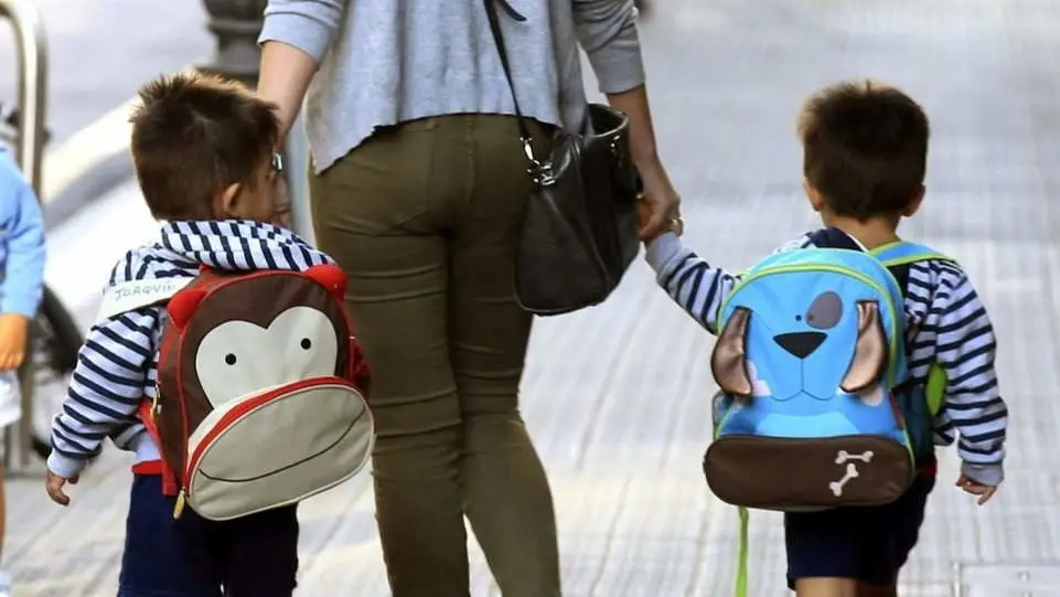 Dos niños, de la mano de una adulta. AEP