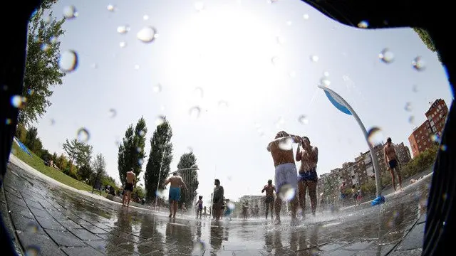 Varias personas se refrescan en una fuente. ZIPI