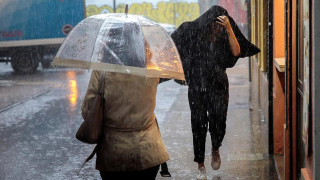 Dos personas se protegen de la lluvia. BIEL ALIÑO