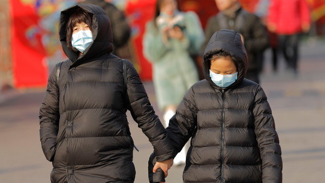 Unha muller e unha nena camiñan por Pequín con máscaras. WU HONG (EFE)