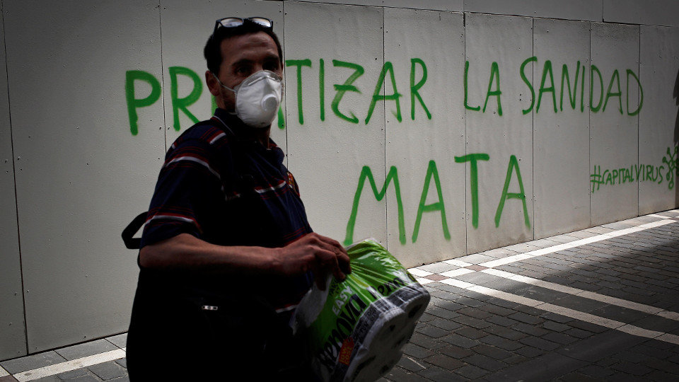 Una persona con mascarilla pasa este sábado en Pamplona por delante de un grafiti. EFE
