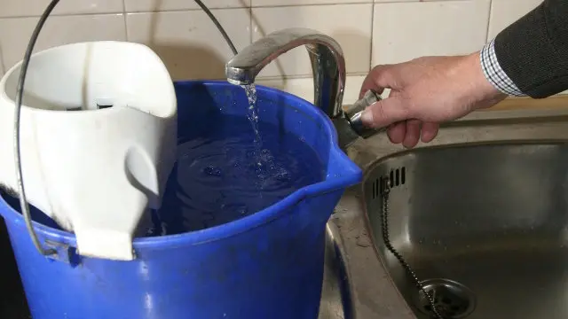 Un hombre llena un cubo de agua.AEP