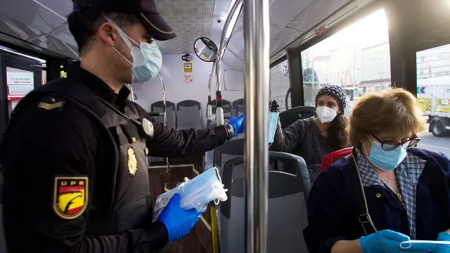 Un axente reparte m&aacute;scaras nun autob&uacute;s urb&aacute;n de Vigo.SALVADOR SAS (Efe)