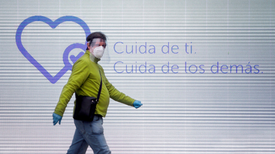 Un hombre camina con mascarilla, guantes y pantalla protectora por una calle del centro de A Coruña. CABALAR (EFE)