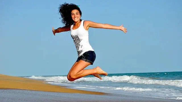 Una joven salta en una playa
