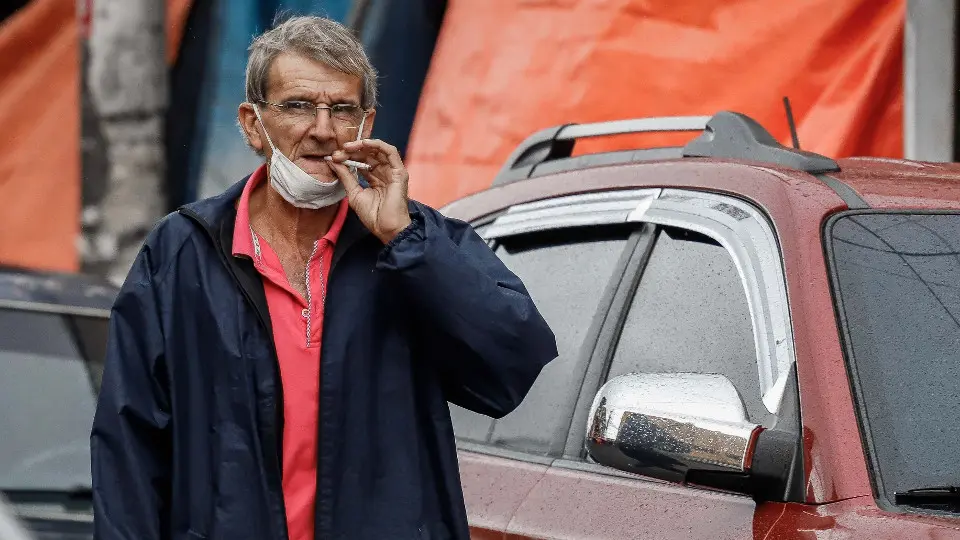Un hombre fuma con la mascarilla en el cuello. EFE