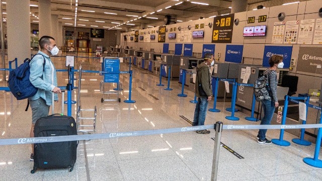 Viaxeiros manteñen a distancia de seguridade antes de facturar a súa equipaxe no interior do Aeroporto de Palma. EFE