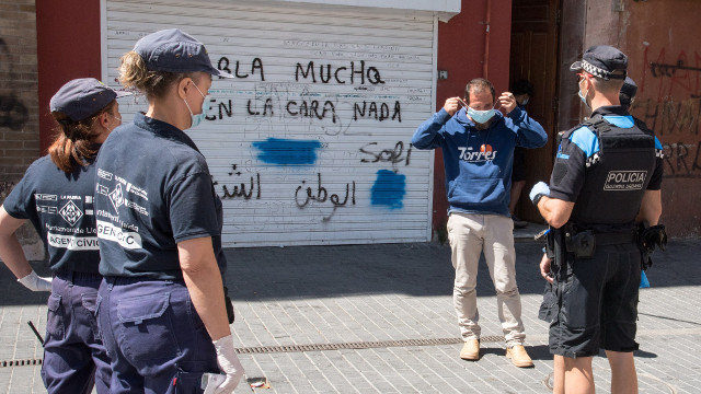 Axentes cívicos  e da Garda Urbana de Lleida entregan unha máscara a un home que non levaba. EFE