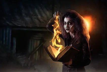 Scary witch holds spellbook, dark powers of witchcraft, spiritual seance. Female foreteller calls the spirits, terrible future teller