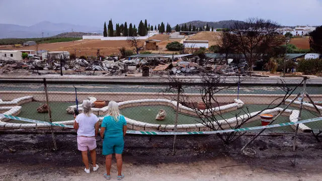 Unas mujeres observan como quedó el cámping tras el incendio. EFE