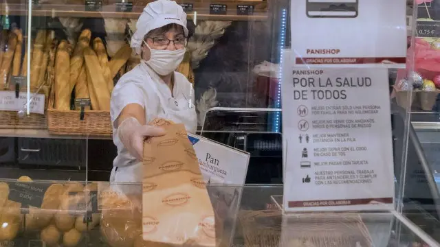 Unha panadeira entrega unha barra tras un biombo. EFE