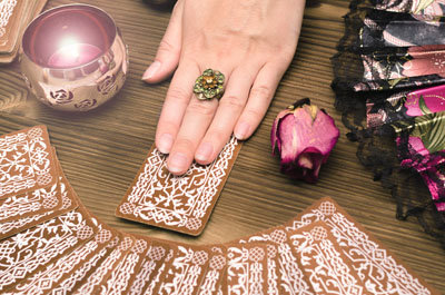 Fortune teller female hands and tarot cards on wooden table. Divination concept. 