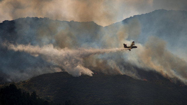 Una avioneta lanza agua sobre el incendio forestal que permanece activo en Lobios. BRAIS LORENZO (EFE)