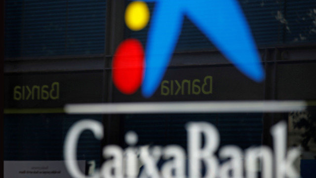 Imagen de una oficina de CaixaBank y otra de Bankia reflejada en el cristal. EFE