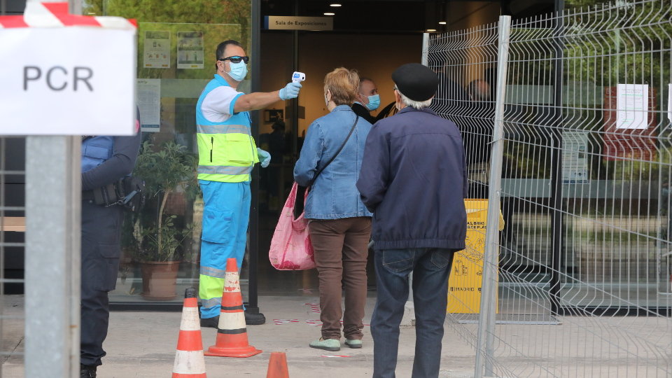 Un trabajador toma la temperatura a los vecinos antes de entrar a realizarse la prueba para detectar el covid en Madrid. EUROPA PRESS