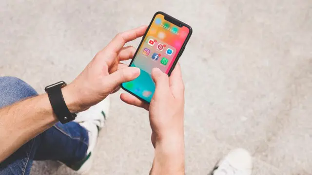 vista-aerea-mano-hombre-usando-aplicacion-medios-sociales-movil_23-2147844468