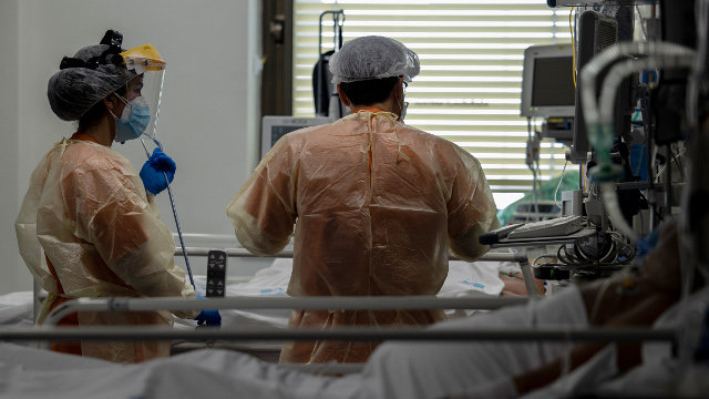 Dos sanitarios atienden a un paciente con coronavirus en un hospital madrileño. EFE