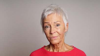 mature woman in her sixties with a skeptical look on her face
