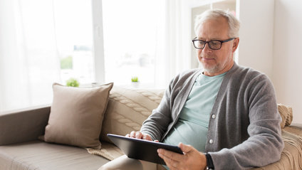technology, old age, people and lifestyle concept - senior man with tablet pc computer sitting on sofa at home