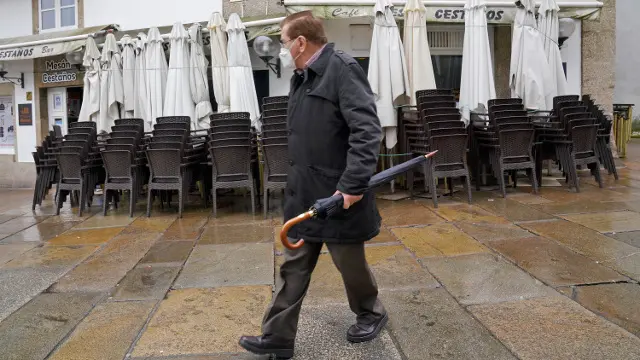 Un hombre pasa junto a un bar cerrado en Santiago. EP