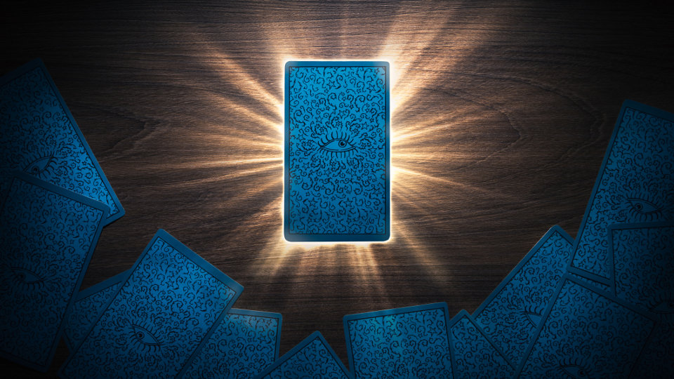 Tarot card facing down on a table with light rays.