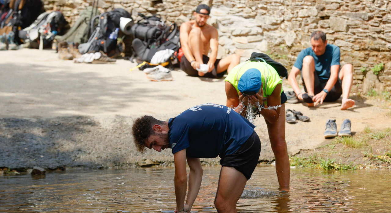 Los peregrinos descansan en un río en Ribadiso, Arzúa, para escapar de la ola de calor. EFE/ LAVANDEIRA JR