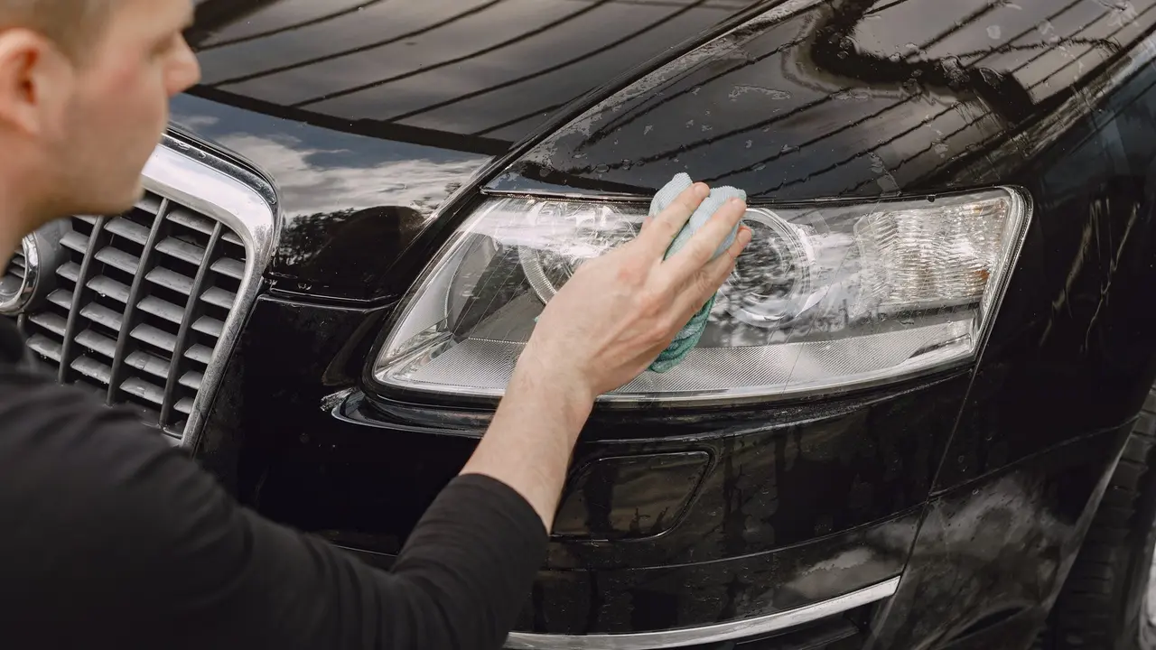 Una persona limpiando los faros de  su coche. FREEPIK