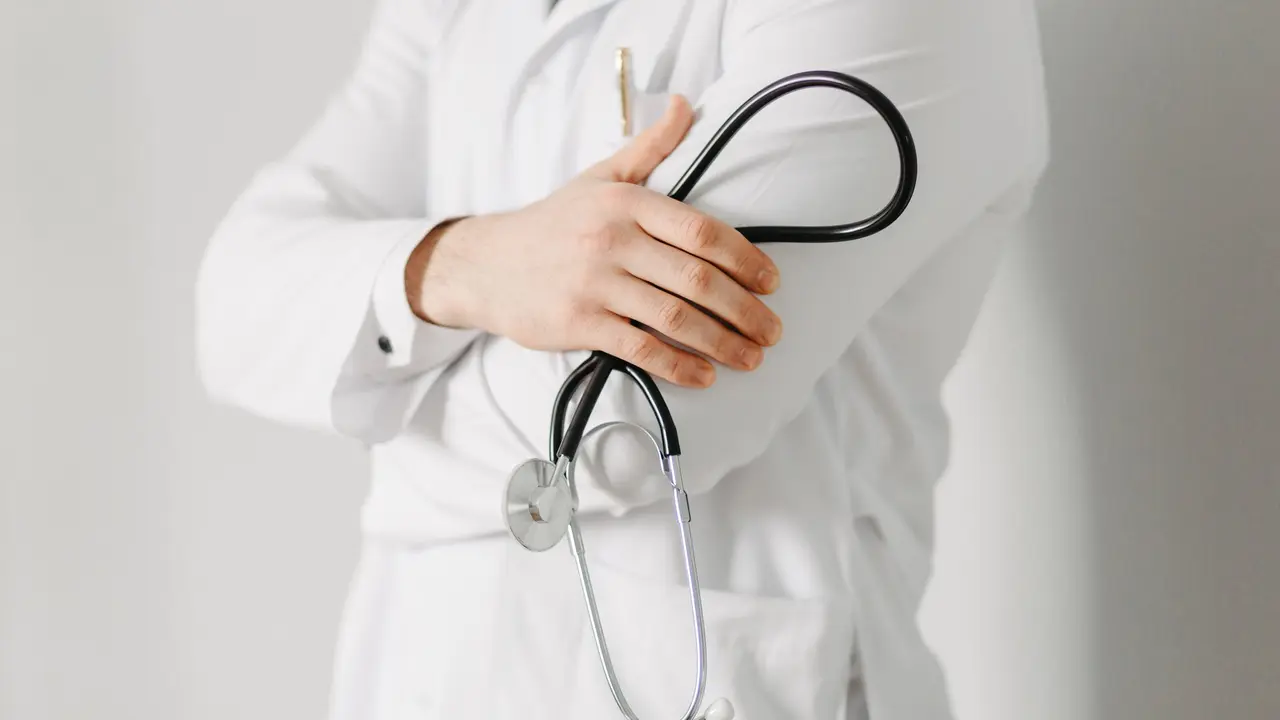 Portrait of a friendly doctor. Isolated on gray