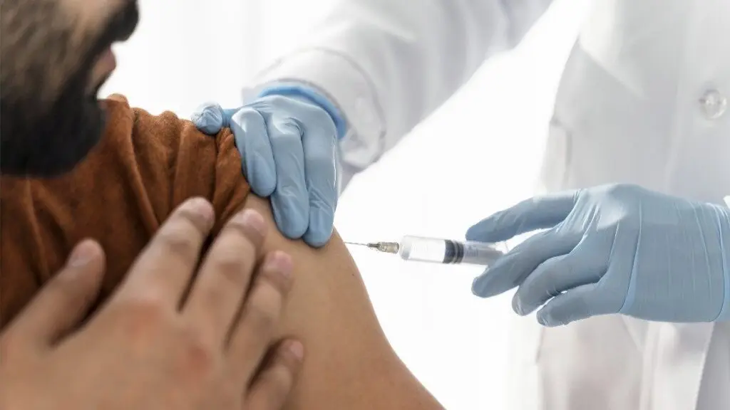 Sanitaria administrando una vacuna a un varón. FREEPIK