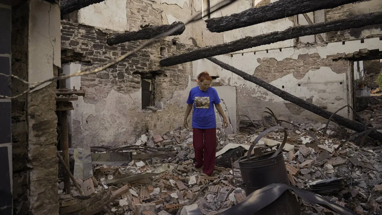 Una mujer observa su casa destruida por el incendio de Larouco. ADRIÁN IRAGO (EUROPA PRESS)