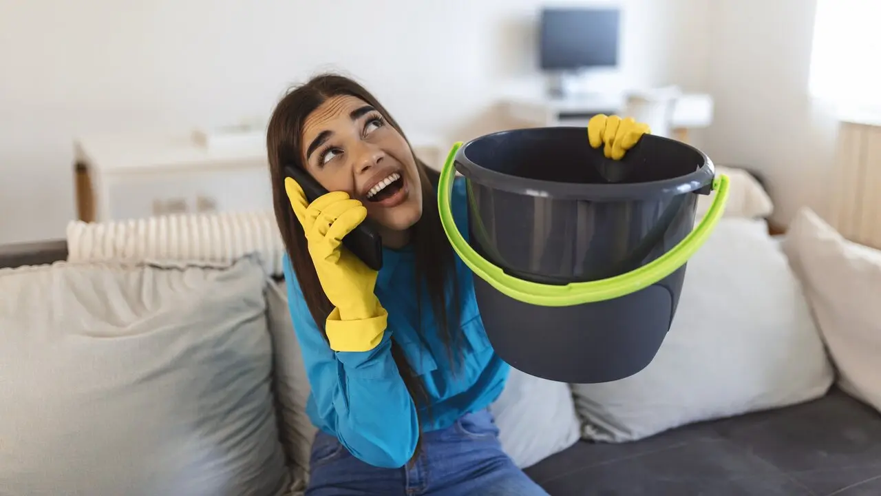 Una mujer sostiene un cubo por un problema de goteras en su vivienda. FREEPIK