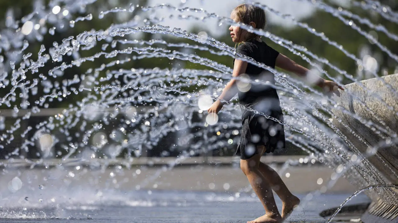 Una menor juega en una fuente. EFE